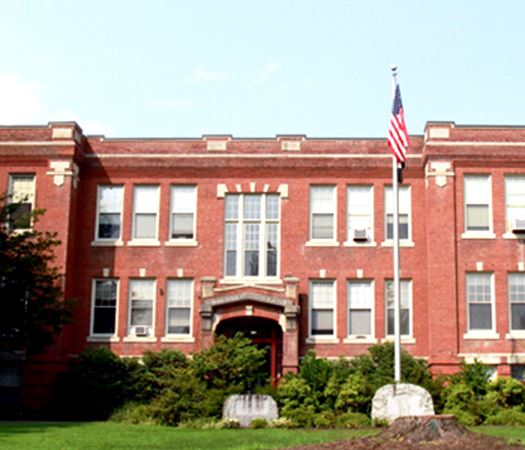 Spotlights Older South Hadley brick building with an American flag in front