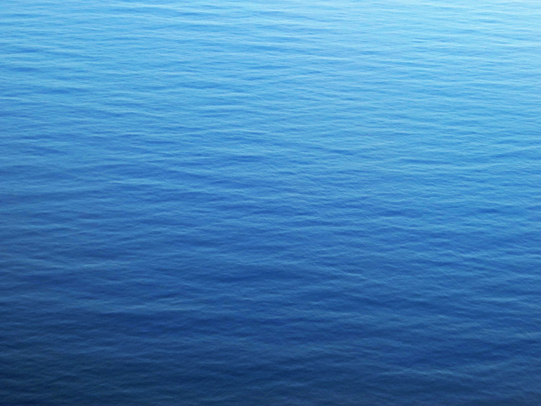 A blue, rippled body of water gradually changes to a lighter blue 