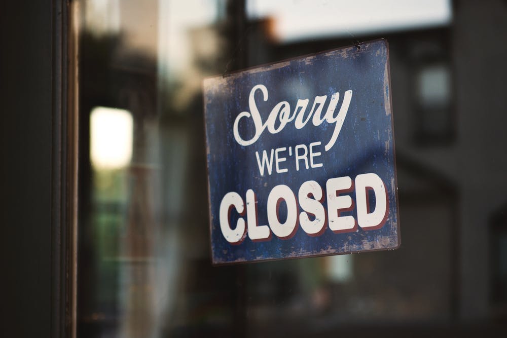 A black sign with white text that reads sorry we're closed