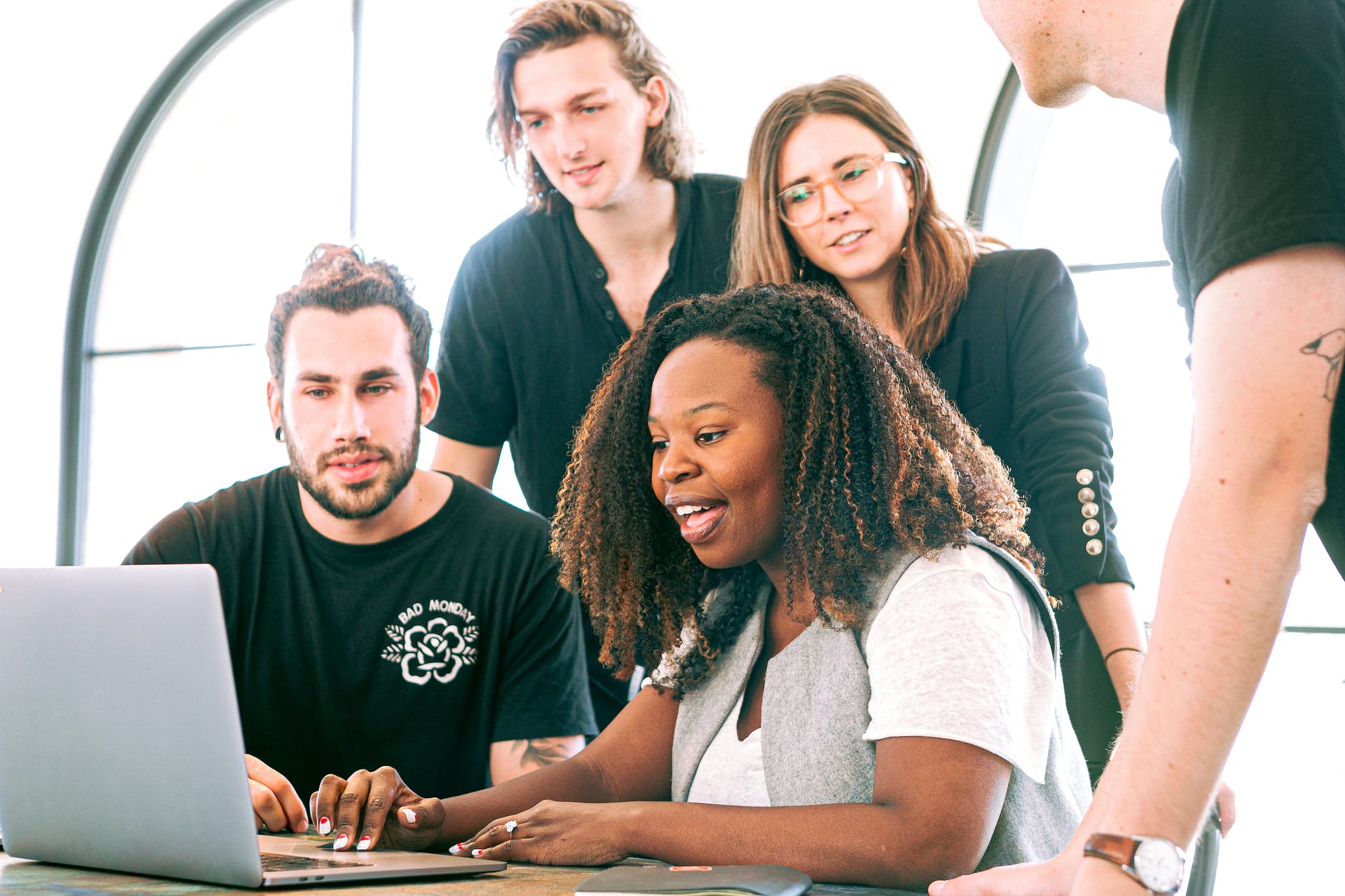 A group of people look at a laptop on a table