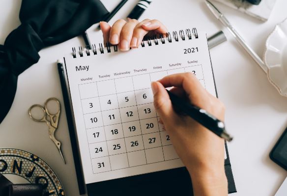 A hand circles a date in a calendar 